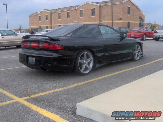 Black coupe with a rear spoiler and custom wheels parked in a lot
