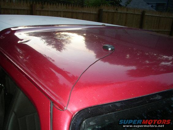 red car roof with a black antenna and a wire running to it