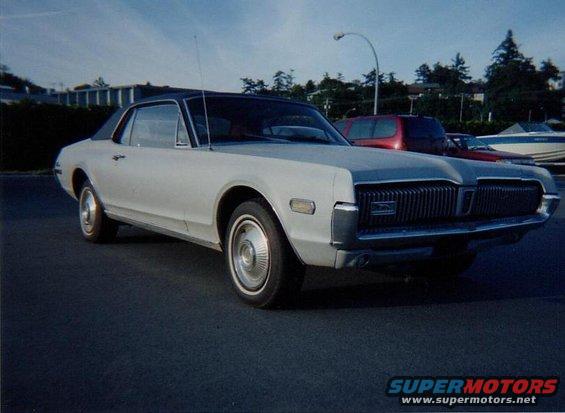 1968 Mercury Cougar, silver with black vinyl top, parked outdoors