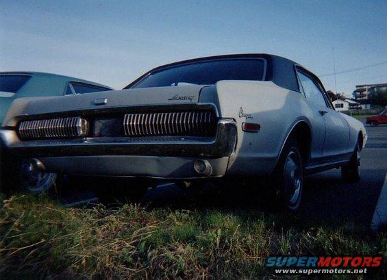 Rear view of a 1967 Mercury Cougar with a black vinyl top, parked next to another car