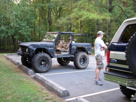Black Ford Bronco with doors removed, parked next to another truck