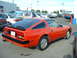 1985 Nissan 300ZX - Rear 3/4 view of a red 1985 Nissan 300ZX. Other cars and a van are visible in the background.