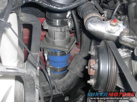 Engine bay with hoses, clamps, and a pulley. Supermotors.net logo visible