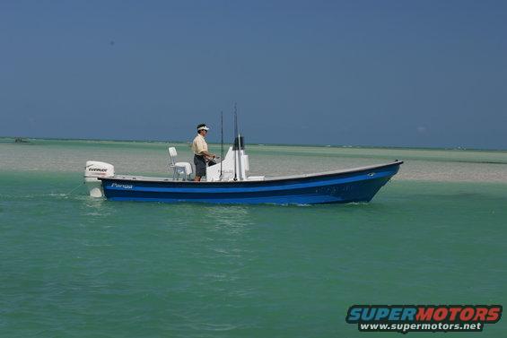 Man driving a blue Panga boat in shallow turquoise water