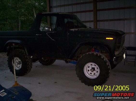 Dark SUV with lifted suspension and large off-road tires, parked indoors