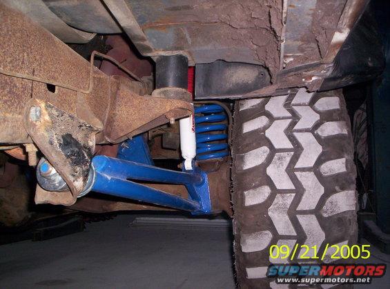 Undercarriage view of blue suspension, Rancho shock, and large tire