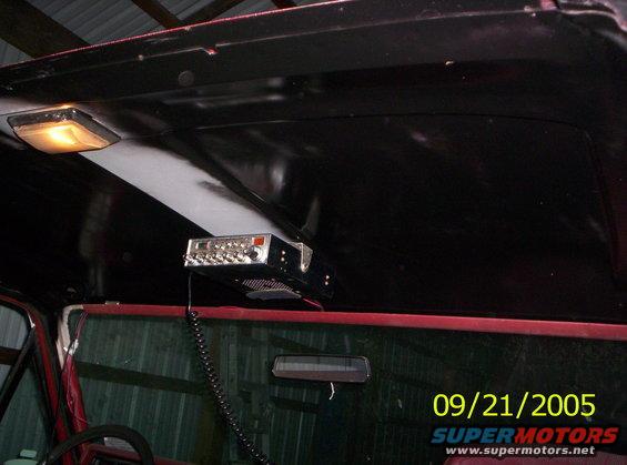 Interior view of a vehicle's headliner with a CB radio mounted and a rearview mirror
