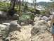 1996 Ford Bronco - A green off-road vehicle is shown traversing a challenging, rocky terrain on a sunny day.