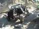 1996 Ford Bronco - An off-road vehicle navigates a rocky trail, its hood open, with another green vehicle visible in the background.