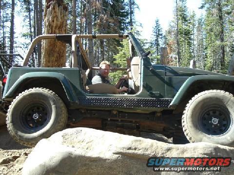 Green Jeep Wrangler off-roading over rocks, driver visible