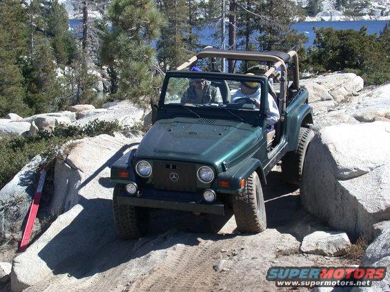Green Jeep Wrangler navigating rocks off-road