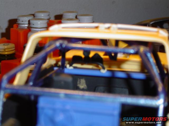 Model SUV interior with blue roll cage and yellow exterior