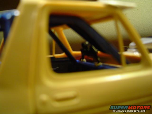 Yellow model car interior with roll cage visible through the window