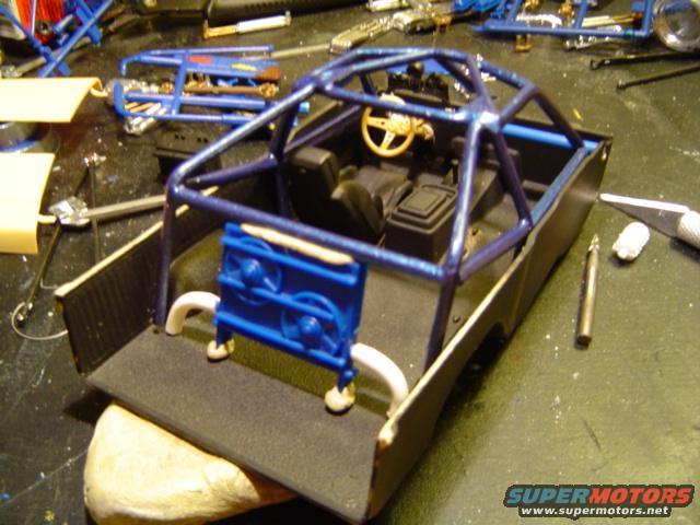 Model car interior with a blue roll cage and a blue engine part in the bed