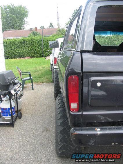Black Ford Bronco parked next to a white truck. Shot from the rear quarter panel