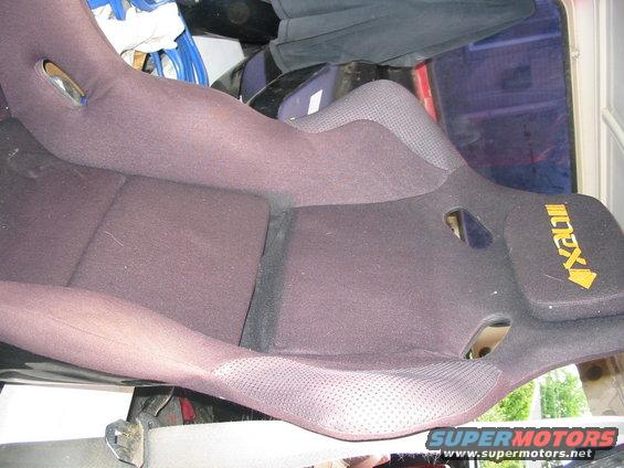 Dark fabric car seat with yellow 'IXIL' logo on headrest