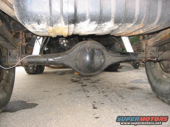 Underside view of a vehicle's rear axle, leaf springs, and fuel tank