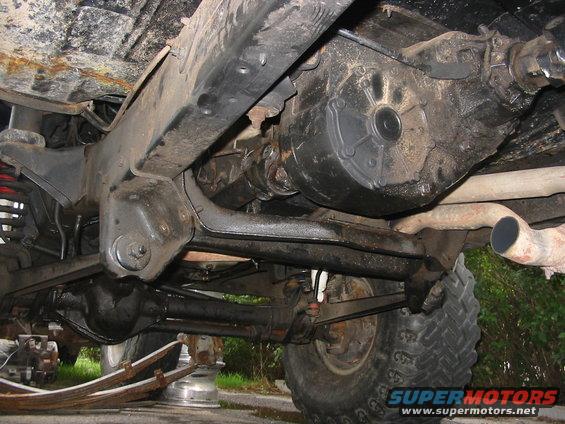 Underside view of a 4x4 vehicle's drivetrain, showing the transfer case, driveshaft, and rear axle