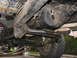 1985 Ford Bronco - The undercarriage of a 4x4 vehicle is visible, with focus on the drivetrain components and suspension.