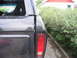 1985 Ford Bronco - Rear view of a dark gray 1978 Ford Bronco, with visible scratches on the body and a reflection of another vehicle.