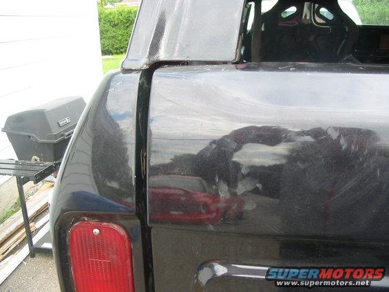 Black SUV rear quarter panel with reflection of a red car