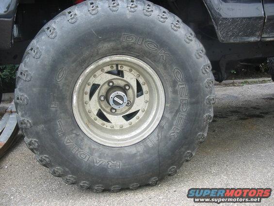 Close-up of a large off-road tire with 'Dick Cepek Radial' text and a multi-spoke wheel with a hub cap