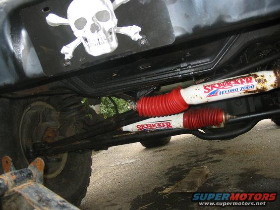 Undercarriage view of Skyjacker Hydro 7000 shocks and red boots, with a skull and crossbones sticker above
