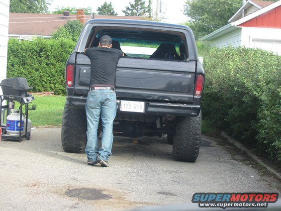 Black Ford Bronco with lifted suspension and large tires. Person looking into the open rear window
