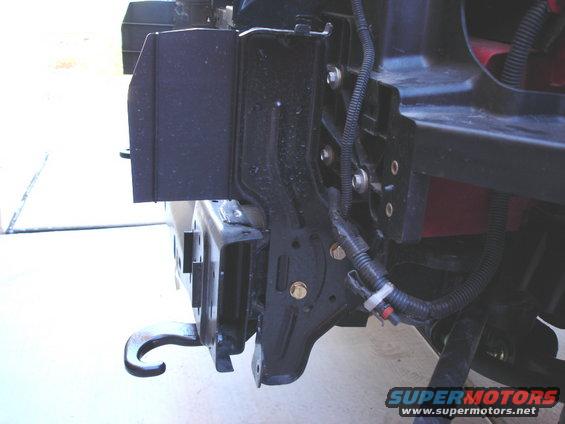 Close-up of a black metal mounting bracket and part of a vehicle frame with wiring harness
