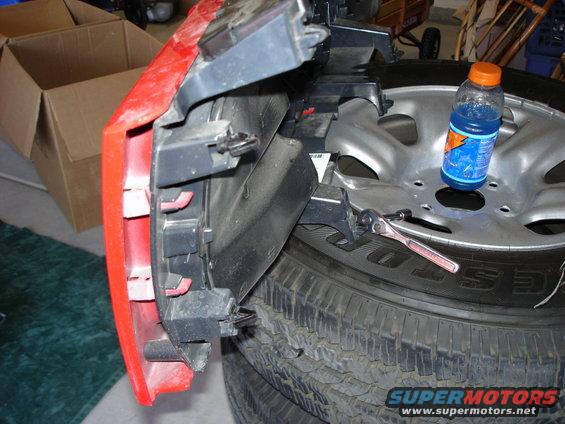 Red bumper part with mounting brackets and a wrench on a tire