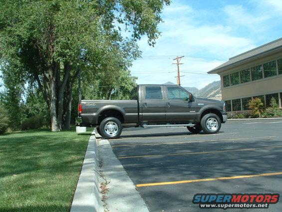 Brown Ford Super Duty pickup truck parked next to a building