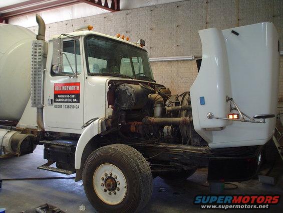 White cement mixer truck with hood open, showing engine. Hollingsworth logo on door