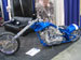 Blue custom motorcycle with chrome engine and large front wheel, viewed from the side
