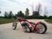 Custom chopper motorcycle with a long front fork and wide rear tire, parked on a paved surface