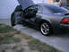2004 Ford Mustang - A dark gray 2004 Ford Mustang coupe is parked with its driver's door and hood open.