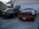 2004 Ford Mustang - Two sports cars, a red Pontiac Firebird and a black Ford Mustang, are parked in front of a garage.