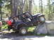 1989 Ford Bronco - A dark blue Jeep Wrangler navigates a rocky obstacle on a wooded trail, with passengers and cargo visible.
