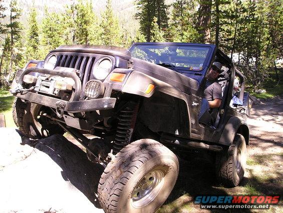 Dark Jeep Wrangler off-roading on a rocky trail