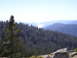1989 Ford Bronco - A vast expanse of forested mountains stretches towards a hazy lake in the distance.