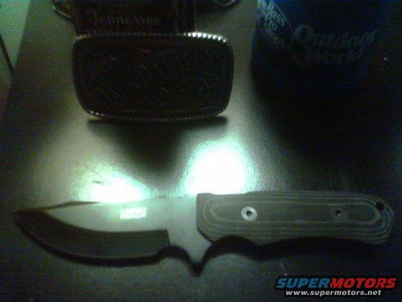 Knife with textured handle and a belt buckle with "Tennessee" text