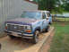 1985 Ford Bronco - This blue Ford Bronco is parked outside a metal building with a wooden fence in the background.