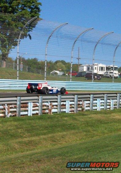 Open-wheel race car with number 14 on its side, blue and white with red accents, on a track