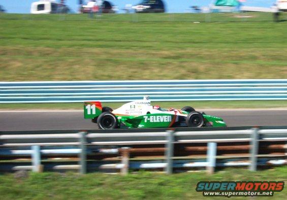 Green and white race car with number 11 and 7-Eleven livery on track