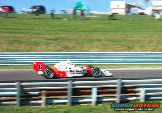 Open-wheel race car with number 6 on the rear wing, red and white livery with Marlboro Team Penske text, on a race track