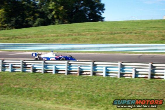 Blue and white open-wheel race car with number 9 on a track