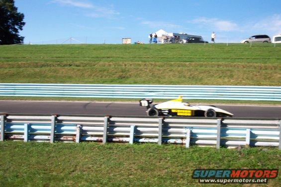 Open-wheel race car with yellow and white body on a track
