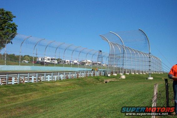 Race track with RVs parked in the background and a yellow race car on the track