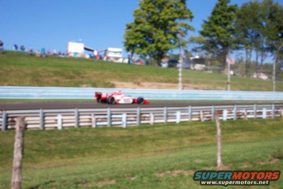 Open-wheel race car on a track with spectators in the background