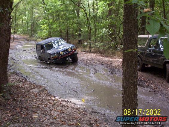 1991 Ford Bronco stuck in a muddy trail, another Bronco visible to the right