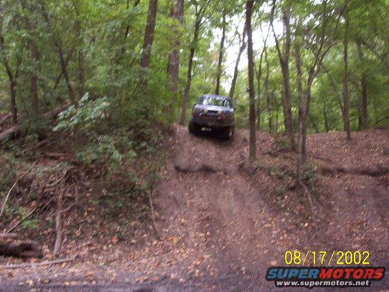 Dark SUV driving downhill on a dirt path in a forest